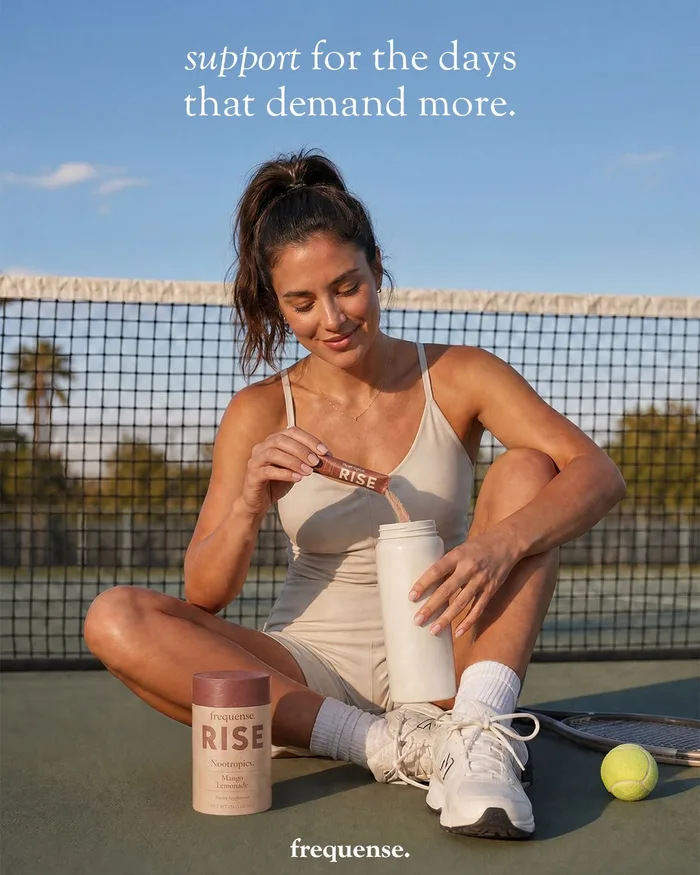 Woman mixing a RISE drink beside a tennis court
